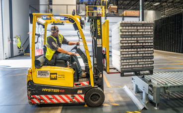 Afbeelding van man op gele heftruck aan het werk in een distributiecentrum