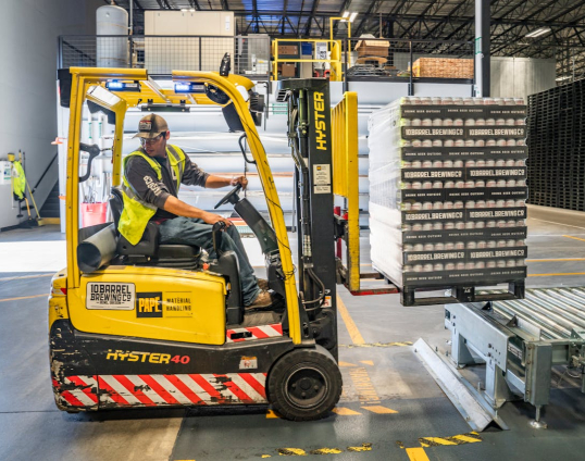 Afbeelding van man op gele heftruck aan het werk in een distributiecentrum