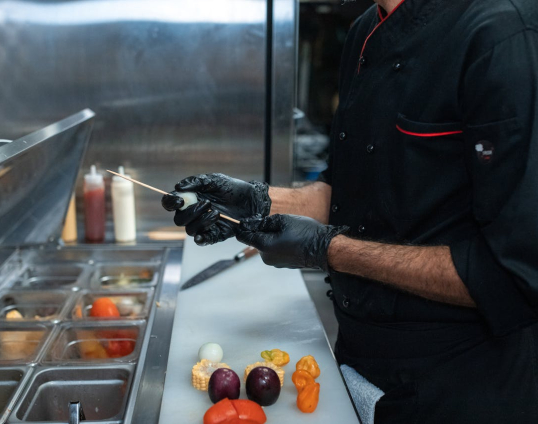 Kok die een groentespies aan het bereiden is in de keuken van een hotel