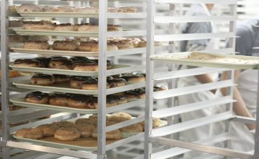 Afbeelding van verse donuts op een industrieel rek in een bakkerij