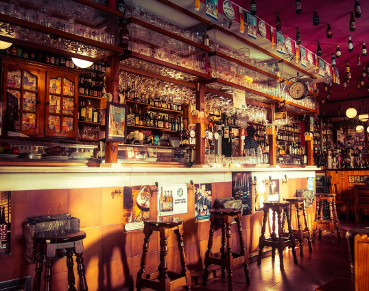 Afbeelding van een bruincafe et drankjes, stoelen en glazen op en rondom de bar.